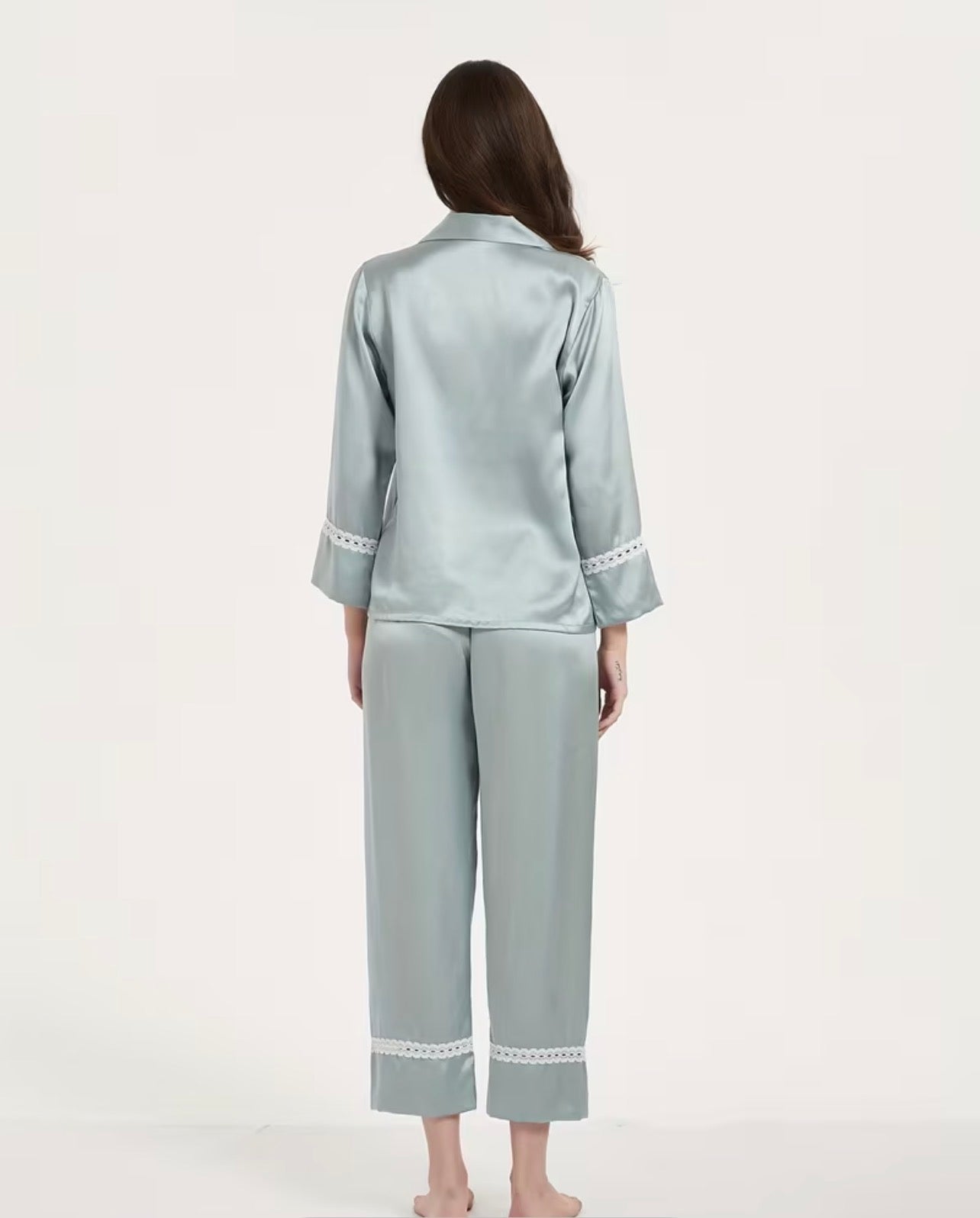 Woman wearing a light blue satin silk pajama set on a white background