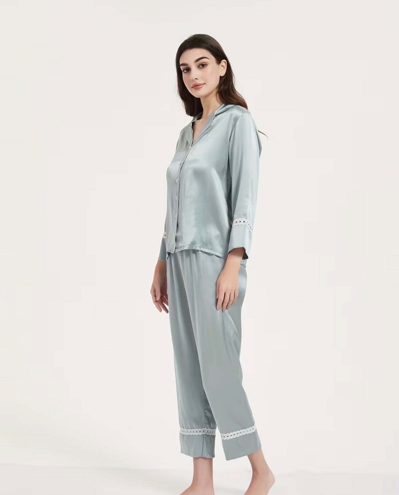 Woman wearing a light blue silk  pajama set on a white background